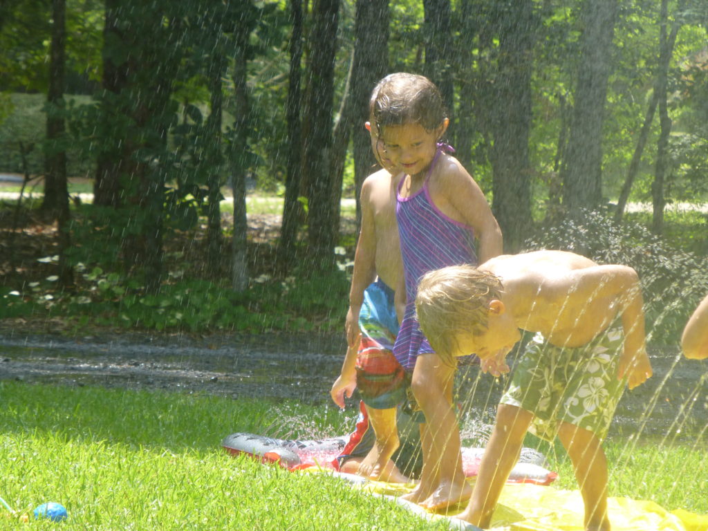 children playing in a lawn sprinkler-Camp CeCE