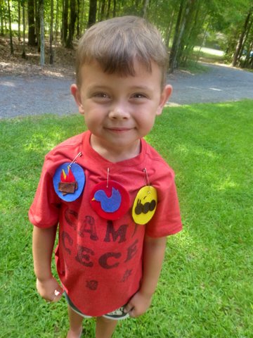 BOY STANDING WITH FELT BADGES PINNED TO HIS SHIRT - CAMP CECE