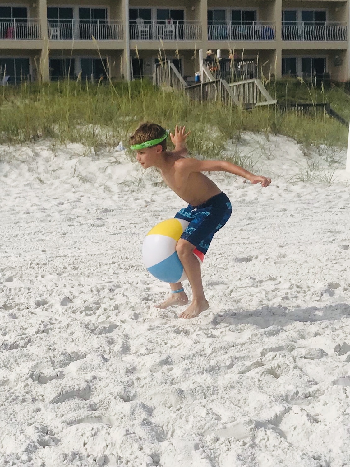boy running with beach ball between his legs-family style cousin camp